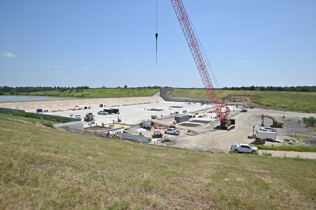 An overhead view of the Lewisville Lake spillway. Construction crews have installed more than 70 high-capacity post-tensioned anchors through the spillway weir and into the underlying bedrock. These anchors increase the spillway's resistance to uplift forces and improve overall structural stability. In addition, engineers installed an upstream geomembrane blanket designed to limit seepage beneath the spillway, reducing water pressures that can develop beneath the concrete during flood operations. Additional improvements include reinforcing portions of the spillway apron with 936 rock dowels and restoring disturbed areas once construction is complete.