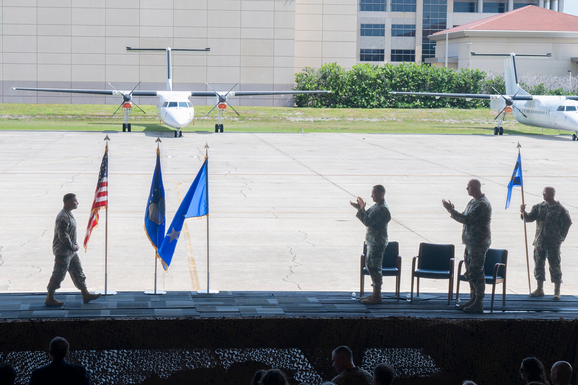 Col. Creighton Mullins (far left), outgoing commander of the Air Force Technical Applications Center, gets a standing ovation from Lt. Gen. Thomas K. Hensley, (center) and Col. Mark Brow (right) after Mullins’ farewell speech during the center’s Change of Command ceremony July 24, 2026.  Also pictured is Chief Master Sgt. Brandon Bitler (far right) guidon bearer and AFTAC’s Command Chief. (U.S. Air Force photo by Matthew S. Jurgens)