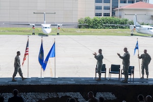 Col. Creighton Mullins (far left), outgoing commander of the Air Force Technical Applications Center, gets a standing ovation from Lt. Gen. Thomas K. Hensley, (center) and Col. Mark Brow (right) after Mullins’ farewell speech during the center’s Change of Command ceremony July 24, 2026.  Also pictured is Chief Master Sgt. Brandon Bitler (far right) guidon bearer and AFTAC’s Command Chief. (U.S. Air Force photo by Matthew S. Jurgens)