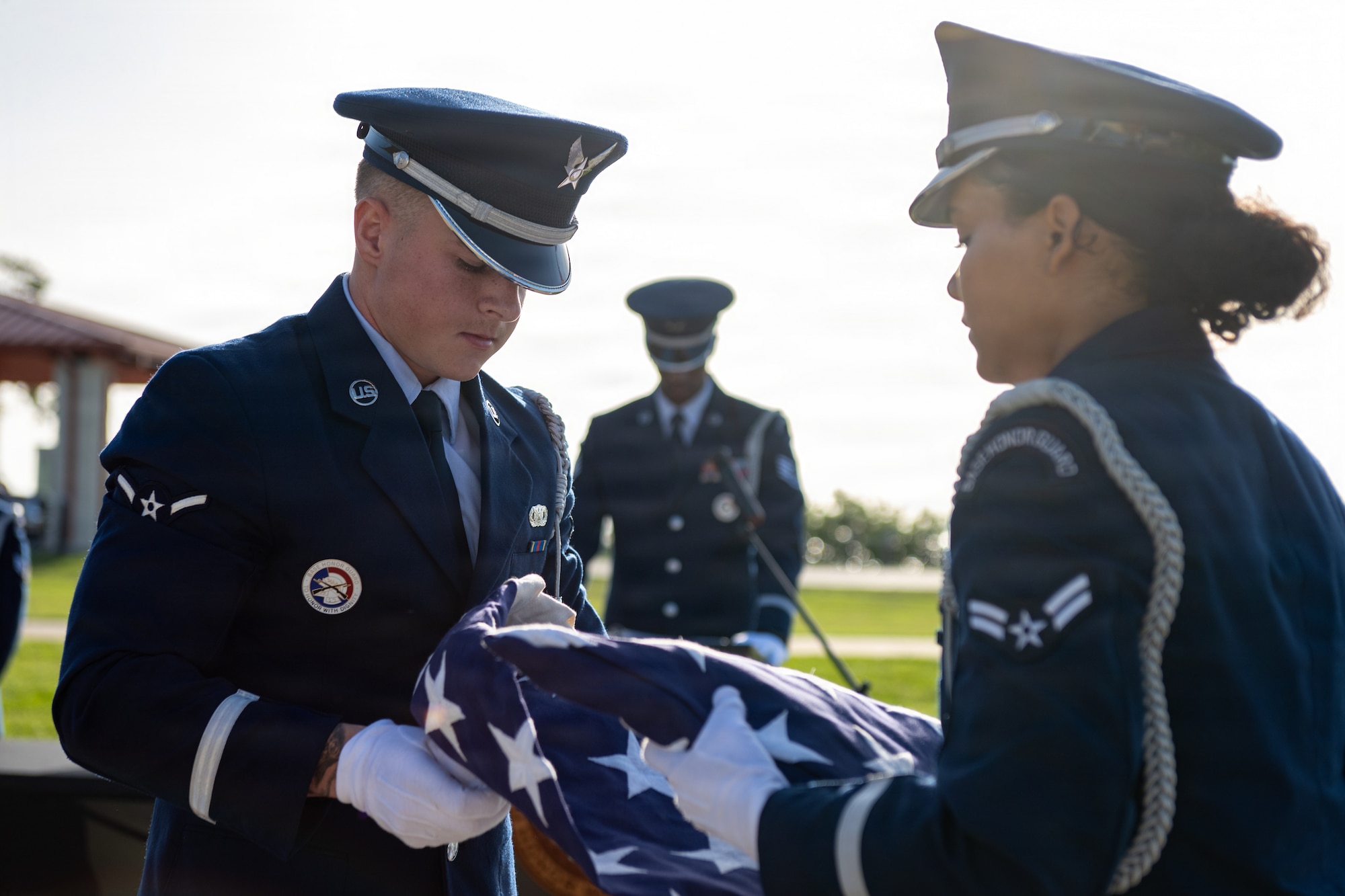 U.S. Air Force Airman Caden Stevens, left, and Airman 1st Class Marie Allegra, 6th Force Support Squadron ceremonial guardsmen, unfold a ceremonial U.S. flag at MacDill Air Force Base, Florida, July 22, 2026. Ceremonial guardsmen perform duties ranging from funeral honors, where one or multiple flags are presented to the next of kin during a funeral, to Colors presentation at local and installation events. (U.S. Air Force photo by Senior Airman Derrick Bole)