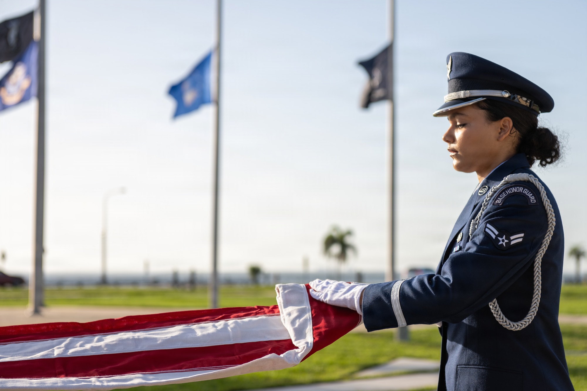 U.S. Air Force Airman 1st Class Marie Allegra, 6th Force Support Squadron ceremonial guardsman, folds a ceremonial U.S. flag during a base honor guard induction ceremony at MacDill Air Force Base, Florida, July 22, 2026. During a ceremonial flag fold, the guardsman will perform 13 precise folds to achieve a small, triangular flag to be given to the deceased’s next of kin during a funeral. (U.S. Air Force photo by Senior Airman Derrick Bole)