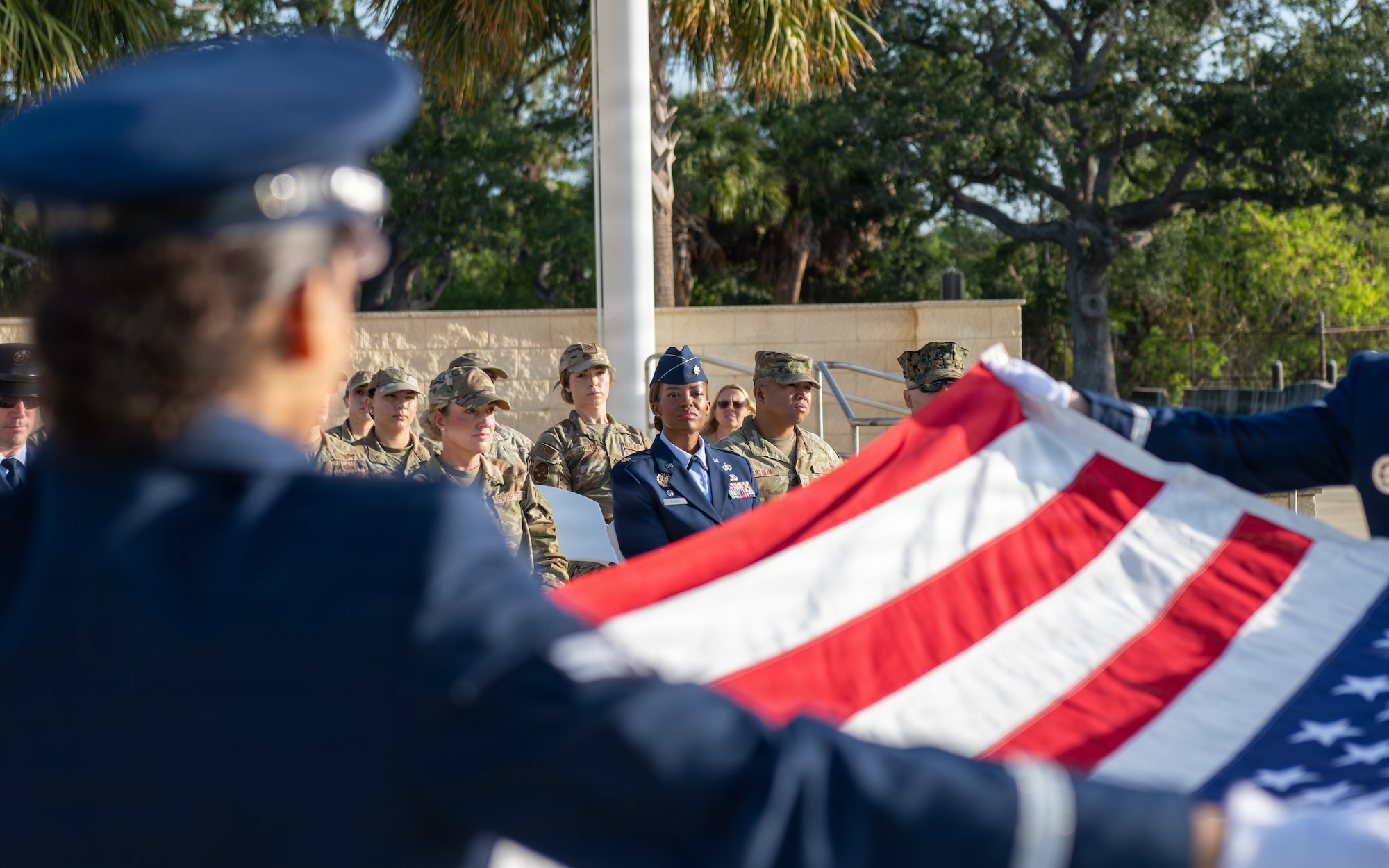 U.S. Air Force Maj. Kenda Gusme, 6th Force Support Squadron commander, watches ceremonial guardsmen assigned to her unit unfurl a ceremonial U.S. flag during a base honor guard induction ceremony at MacDill Air Force Base, Florida, July 22, 2024. Gusme served both in the USAF Honor Guard and the base honor guard at Spangdalem Air Force Base, Germany, and impressed upon the new guardsmen the importance of their position. (U.S. Air Force photo by Senior Airman Derrick Bole)