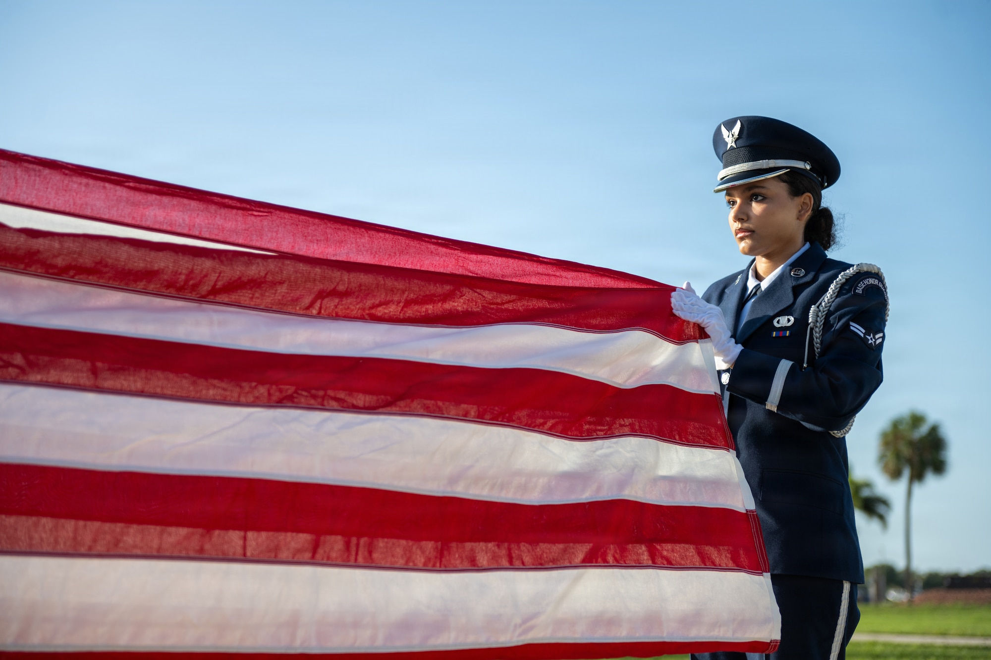 U.S. Air Force Airman 1st Class Marie Allegra, 6th Force Support Squadron ceremonial guardsman, folds a ceremonial U.S. flag during a base honor guard induction ceremony at MacDill Air Force Base, Florida, July 22, 2026. During a ceremonial flag fold, the guardsman will perform 13 precise folds to achieve a small, triangular flag to be given to the deceased’s next of kin during a funeral. (U.S. Air Force photo by Senior Airman Derrick Bole)