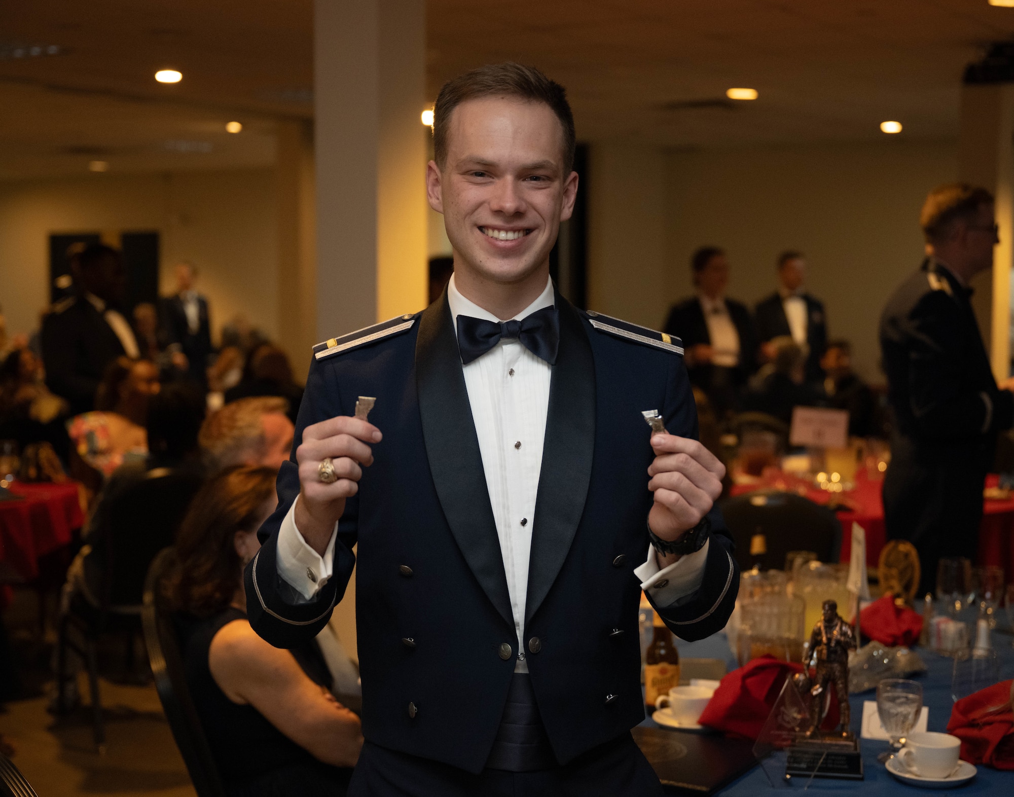 U.S. Air Force 2nd Lt. Grant McIntosh, 47th Student Squadron student pilot, holds up their broken silver wings during the graduation ceremony of Class 26-14 and 26-12 AU at Laughlin Air Force Base, Texas, July 23, 2026. Graduating student pilots received silver wings as a symbol of successfully completing Undergraduate Pilot Training. (U.S. Air Force photo by Airman 1st Class Darryl Keith)