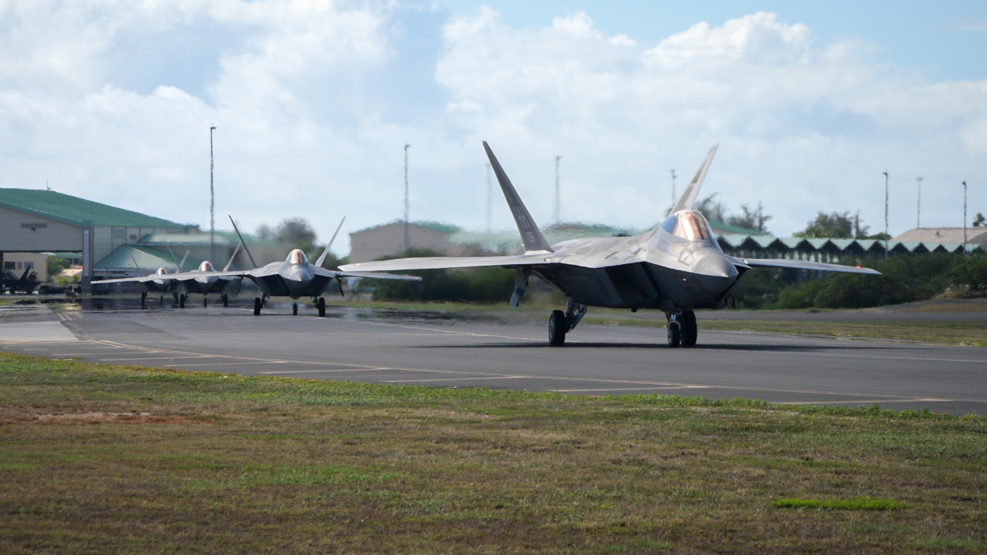Four fighter jets drive in a row taxi down a flightline ramp for takeoff.