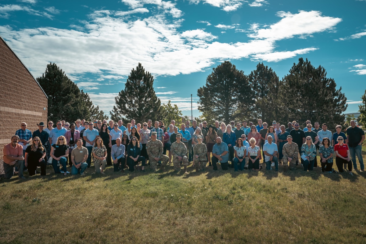 about one hundred people pose for a photo in a grass field