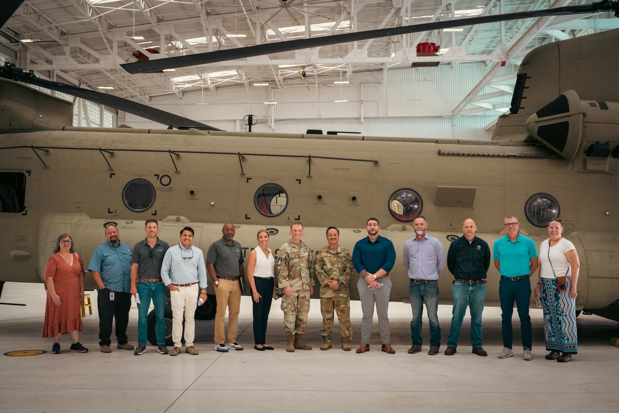 13 people pose for a photo in front of a helicopter