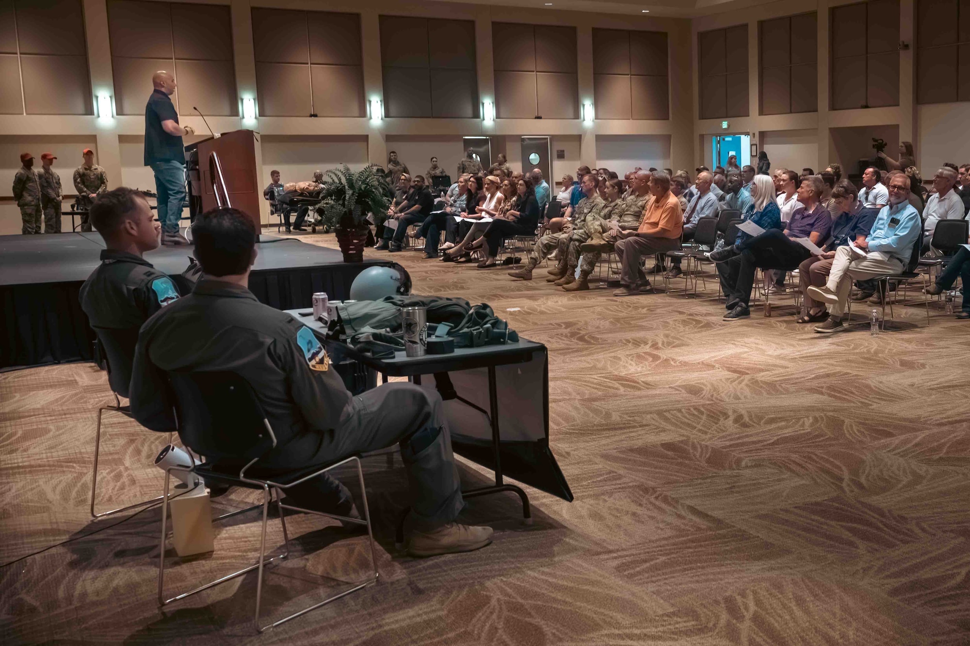 about one hundred people sit in audience while a man stands on stage