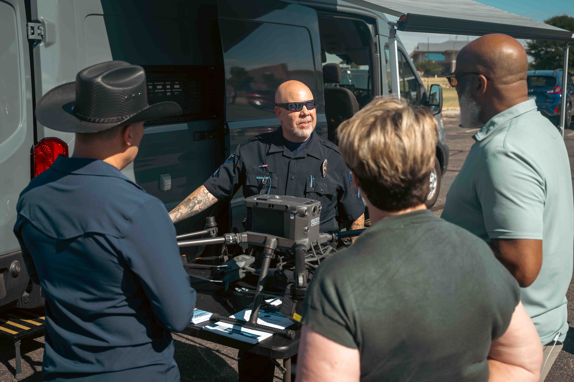 3 people attend a briefing of a drone by a police officer