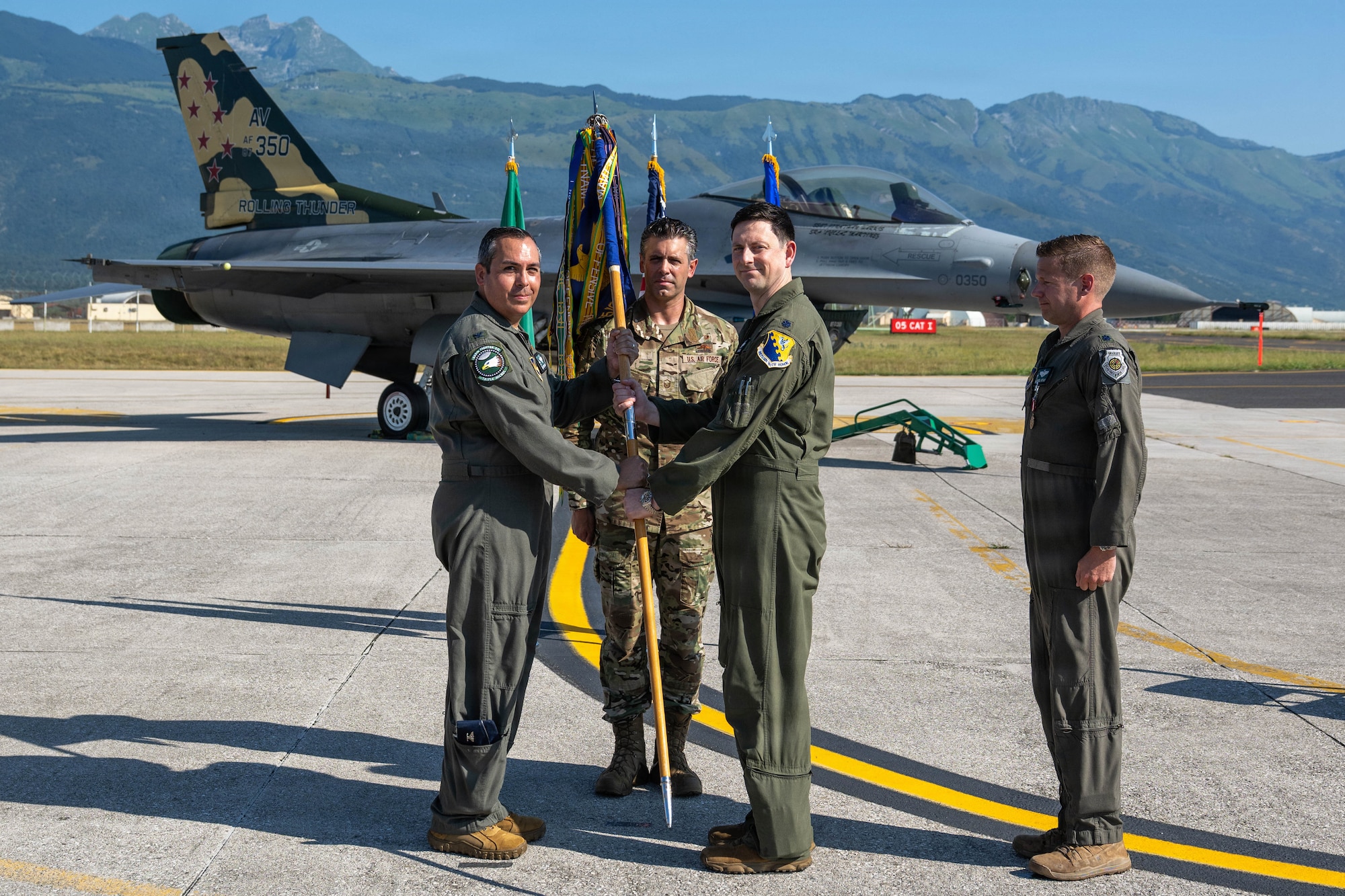 A man hands a guidon to another man.