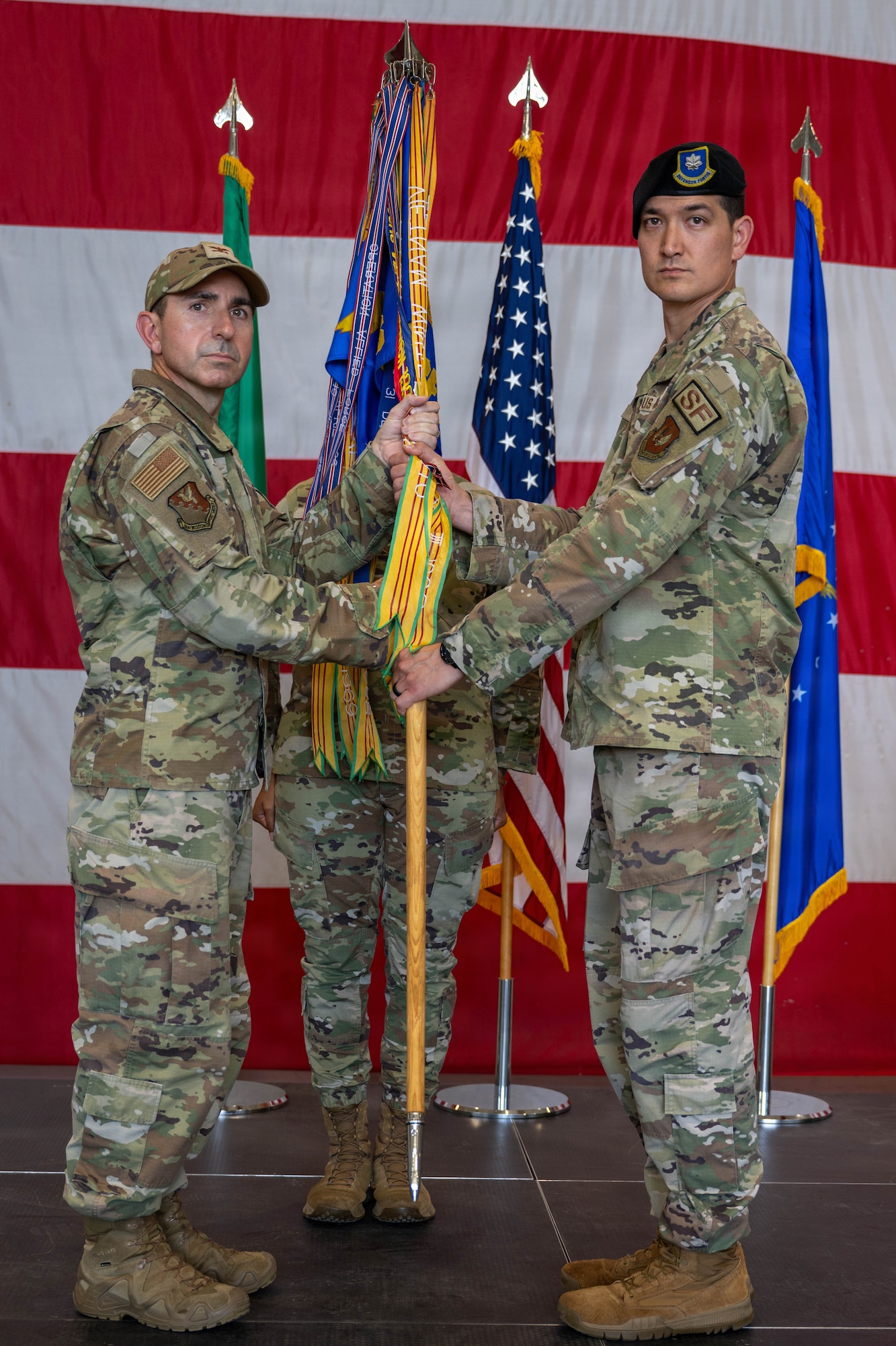 A man hands a guidon to another man.