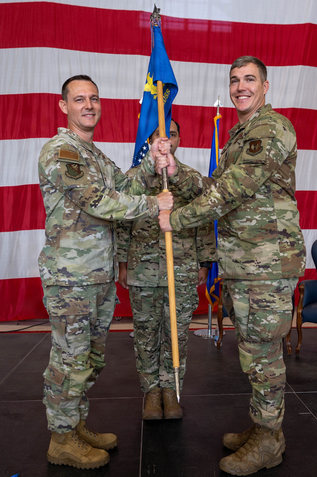 A man hands a guidon to another man.