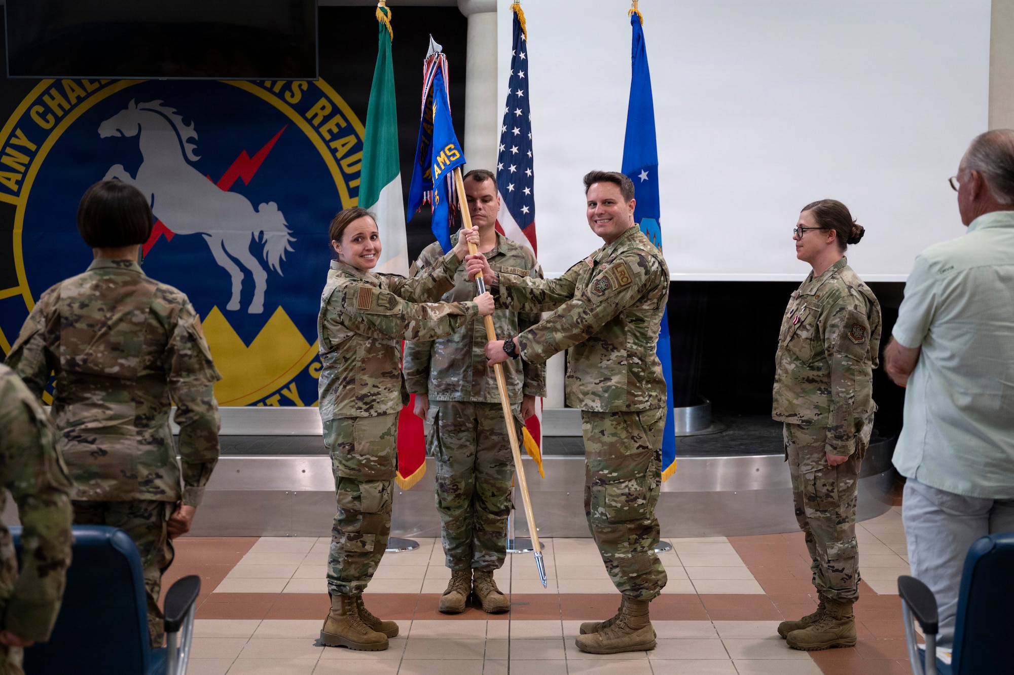 A woman hands a guidon to a man.