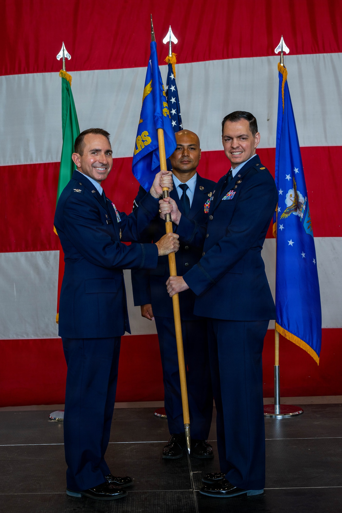 A man hands a guidon to another man.