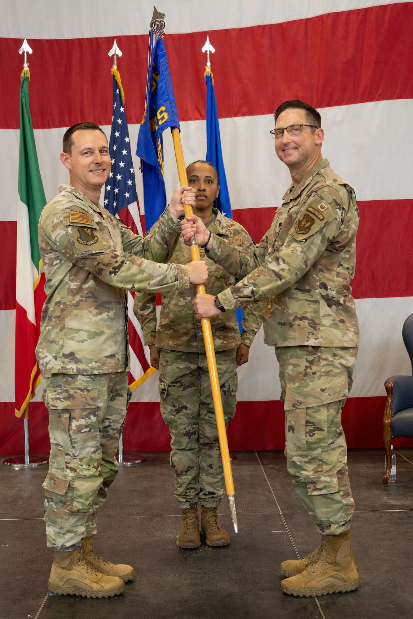 A man passes a guidon to another man.
