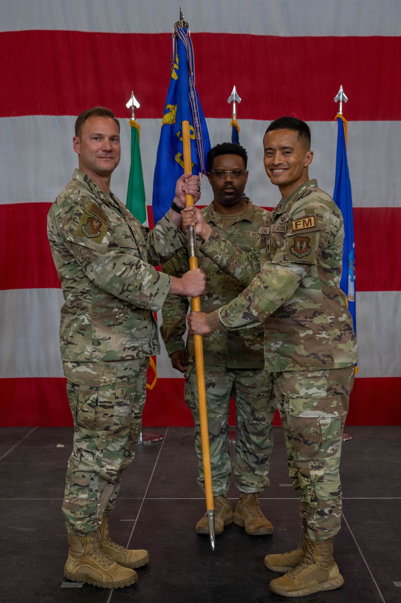 A man hands a guidon to another man.