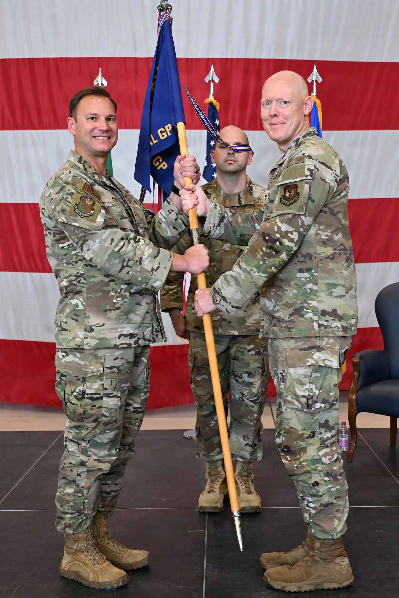 A man hands a guidon to another man.