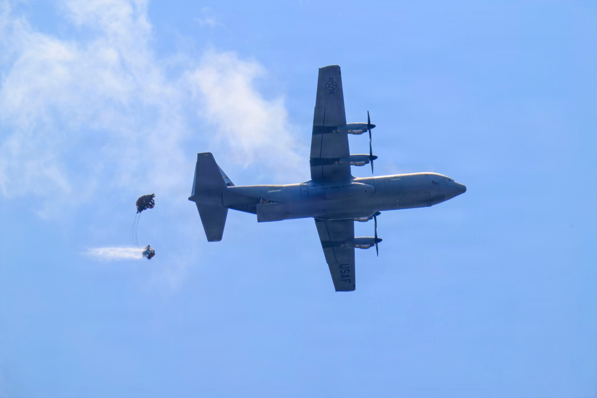 A C-130J-30 flying over a drop zone.