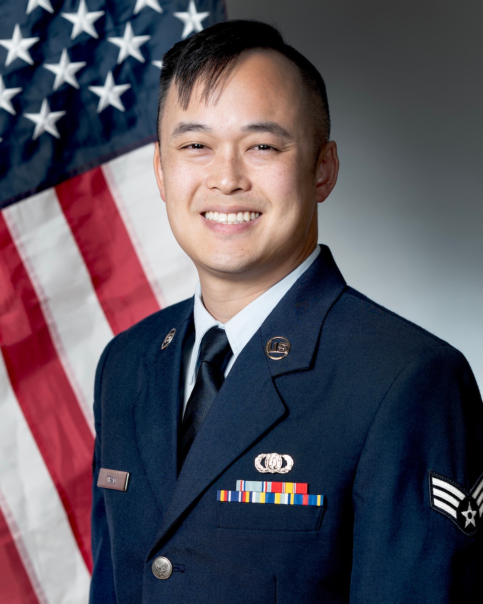 An airman poses in front of the U.S Flag