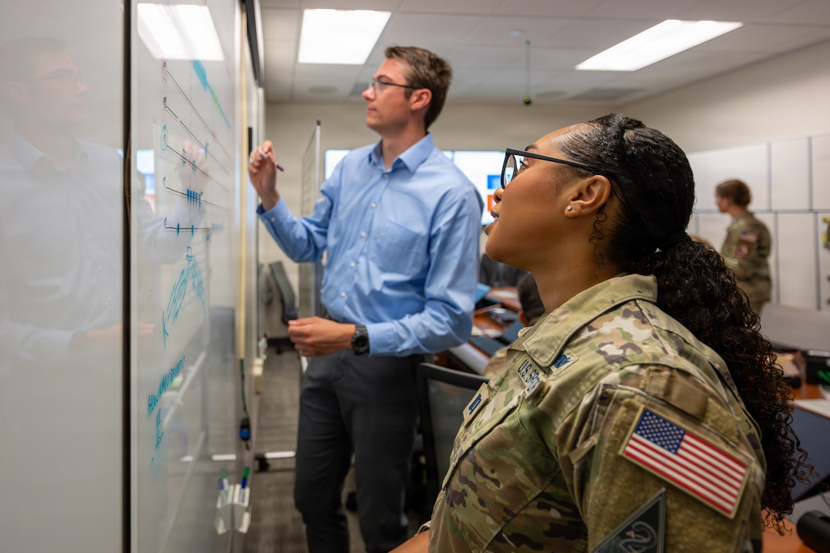 U.S. Space Force Capt. Destiny Kim, 18th Space Defense Squadron, and Joseph McNaughton, National Space Intelligence Center, collaborate on a white board.