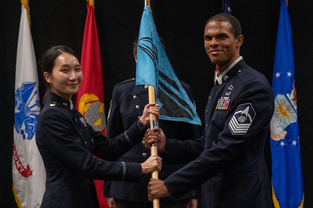 U.S. Space Force Maj. Uiri Han, 533rd Training Squadron, Detachment 1 commander, passes the guidon to Master Sgt. Justin Young, incoming detachment senior enlisted leader, during the change of responsibility ceremony at Goodfellow Air Force Base, Texas, July 21, 2026. As senior enlisted leader, MSgt.Young will advise the detachment commander on the readiness, professional development, and welfare of the detachment's Guardians. (U.S. Air Force photo by Senior Airman James Salellas)