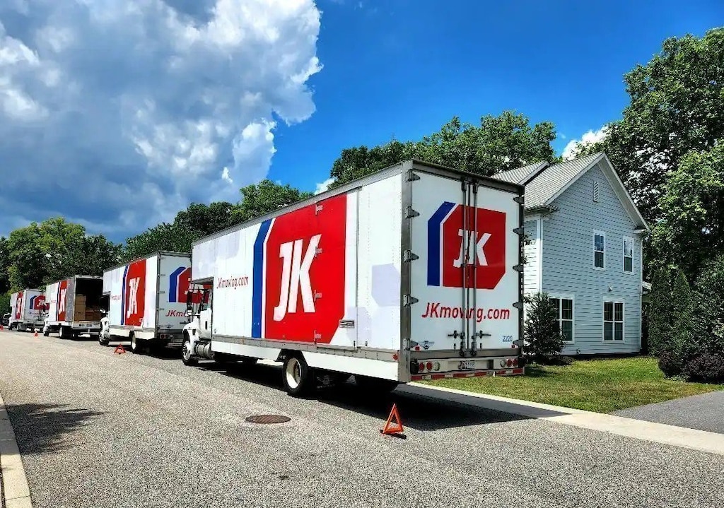 A large moving truck parked on the street in front of a row of suburban military family housing units.