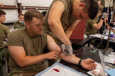 U.S. Army Cpt. Dan Walton, assigned to the Fort Hood Family Medicine Residency, inspects the needle inserted into the U.S. Army Soldier, Joseph Smith, assigned to the 19th Army Health Center, to ensure the needle was put in safely on Fort Hood, Texas, Jun. 1, 2026. JEMX-26 provides interoperability across Army, Navy, and Air Force medical teams and NATO partners with unparalleled hands-on training in combat casualty care. This rigorous, multi-service training prepares military medical personnel to operate and deliver critical care in challenging, complex operational environments. (U.S. Army photo by Sgt. Adel Pacheco Alvarez)