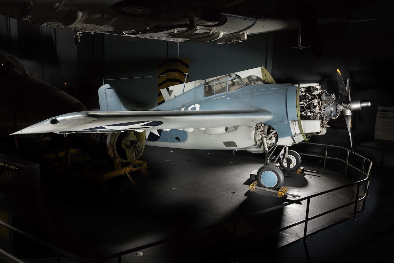 A propeller aircraft is displayed in a dark museum with a spotlight shining on it.