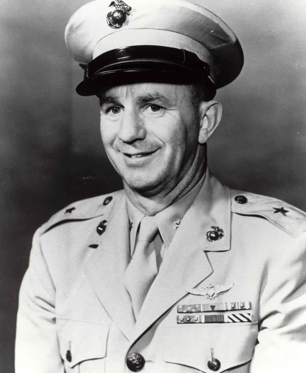 A man in a formal military uniform poses for a photo.