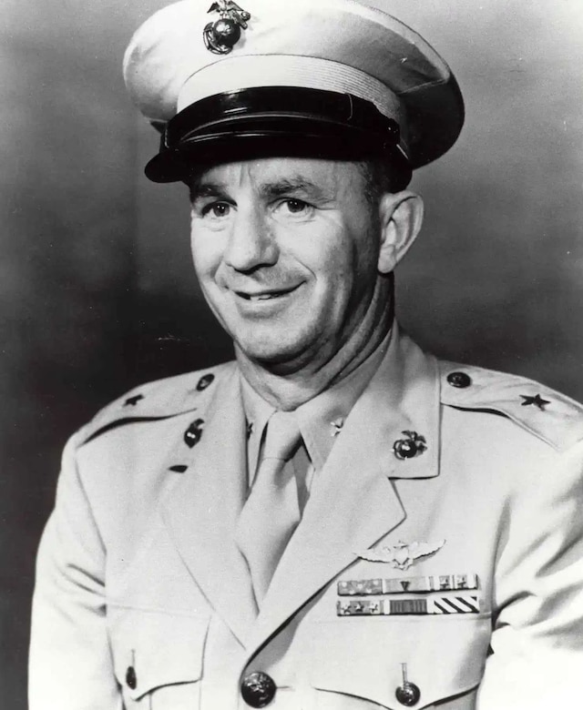 A man in a formal military uniform poses for a photo.