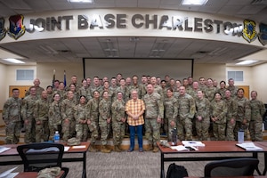A group of uniformed Air National Guard members pose for a photo under a sign that says Joint Base Charleston
