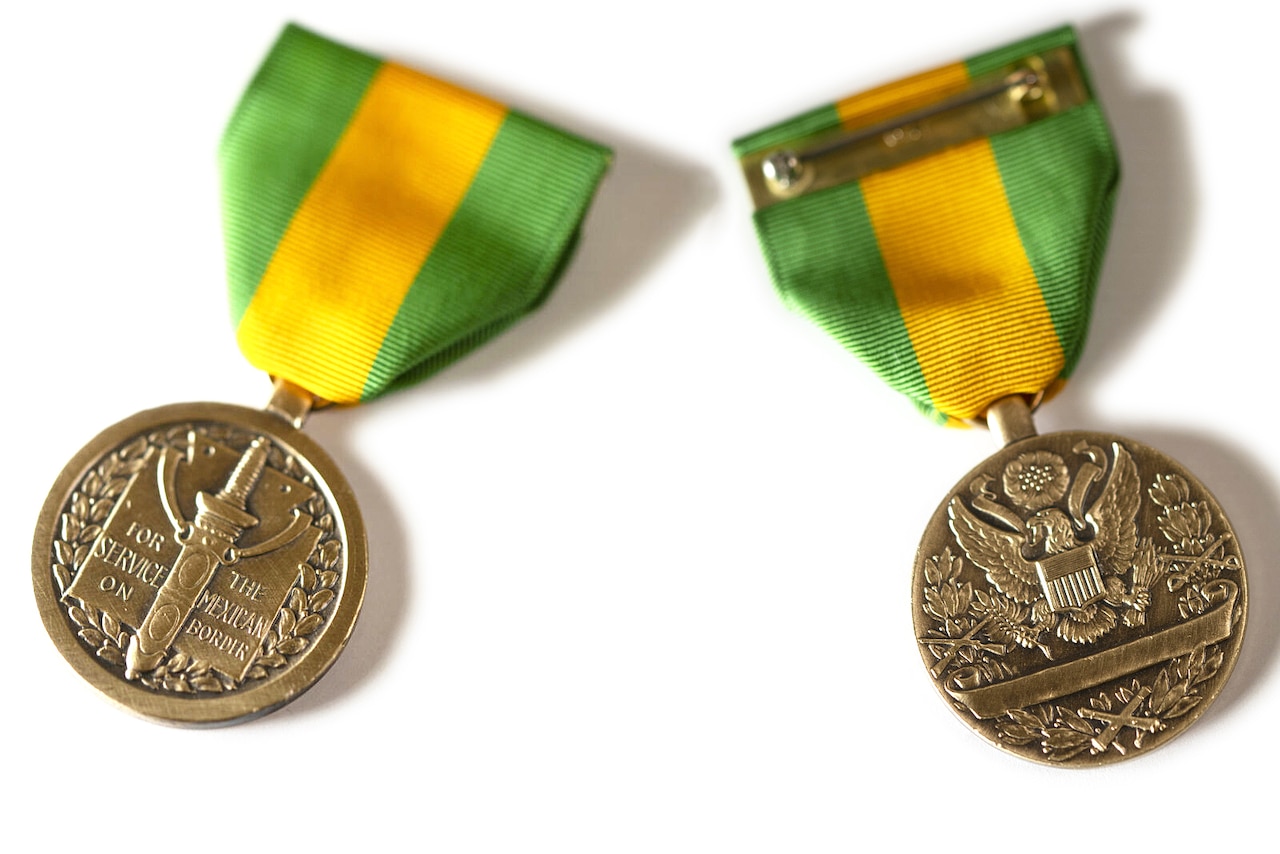 A medal has a yellow and green ribbon.
