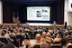 U.S. Air Force Col. John E. Burrell, 5th Bomb Wing commander, addresses members of the 5 BW at an all-call July 23, 2026, at Minot Air Force Base, North Dakota. Burrell also Airmen of current and upcoming wing events, while also answering questions from the audience. (U.S. Air Force photo by Senior Airman Kendra A. Ransum)
