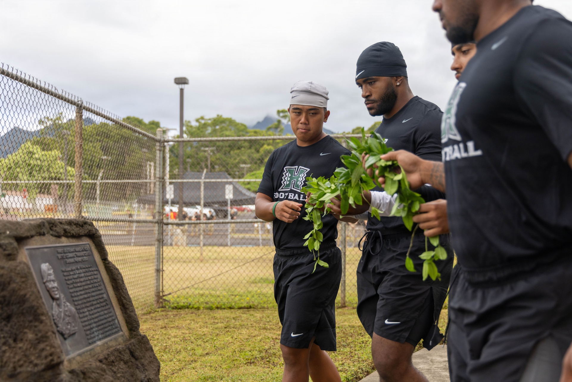 University of Hawaii Rainbow Warrior football players prepare to place a Maile lei on 1Lt. Nainoa K. Hoe memorial stone during the opening ceremony for a team-building day at the 1st Lt. Nainoa Hoe Mission Training Complex on Schofield Barracks, Hawaii, July 24, 2026.