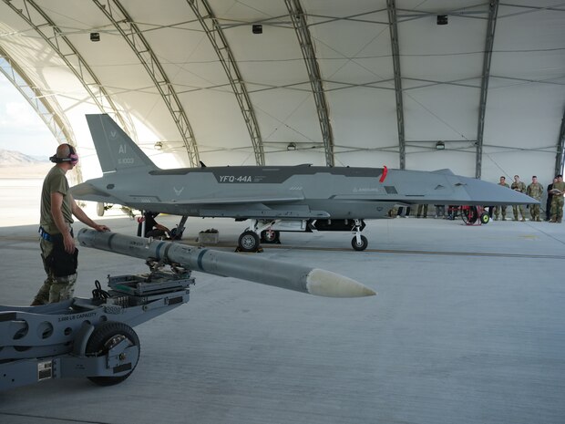 A U.S. Airman aligns a missile to load onto a YFQ-44A Fury aircraft.