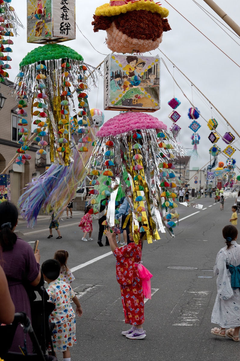 A young girl plays with a hanging street decoration at a festival