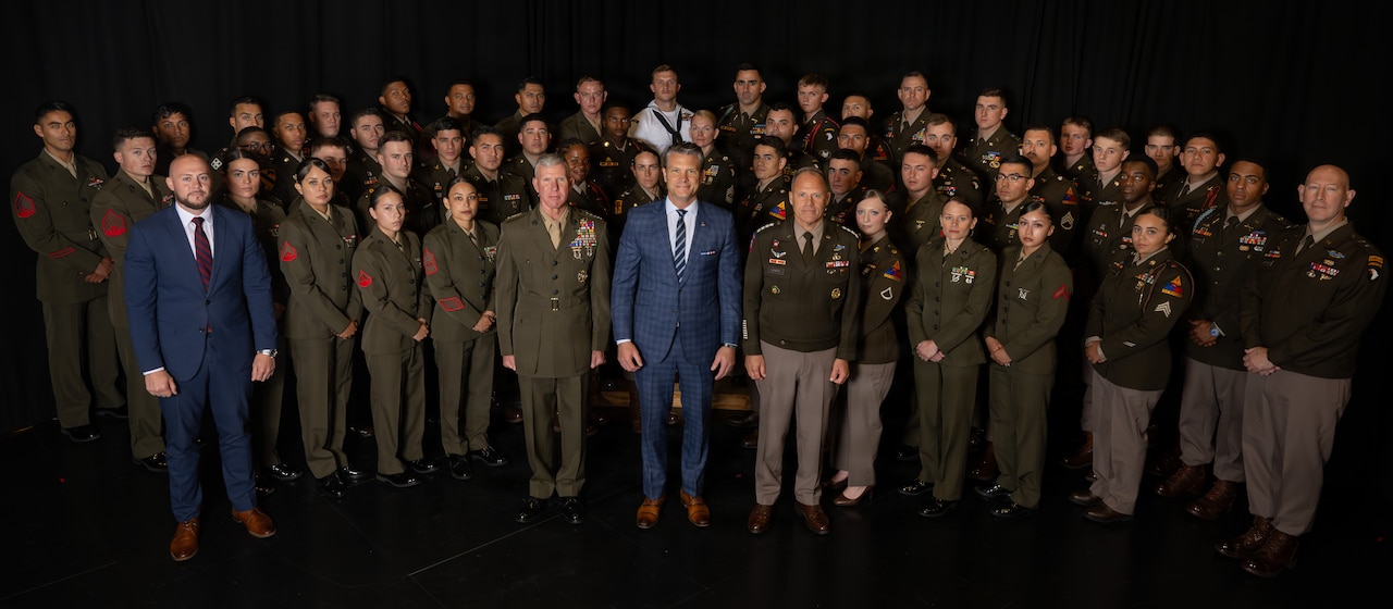 Dozens of uniformed service members and two civilians stand in a group.