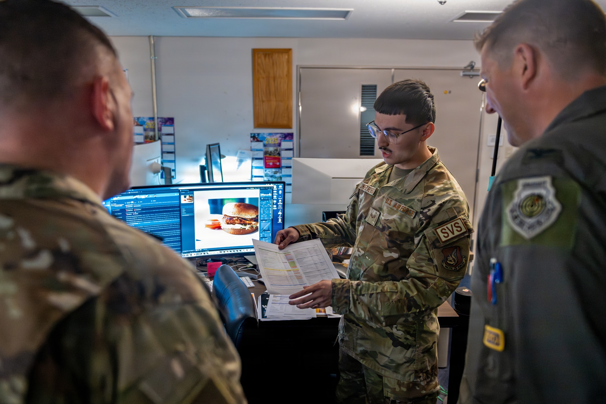 U.S. Air Force Senior Airman Edwin Jiminez Reyes, 35th Force Support Squadron marketing and publicity communications specialist, center, explains ongoing projects for the marketing office to 35th Fighter Wing leadership during a Wild Weasel Walk-Through.