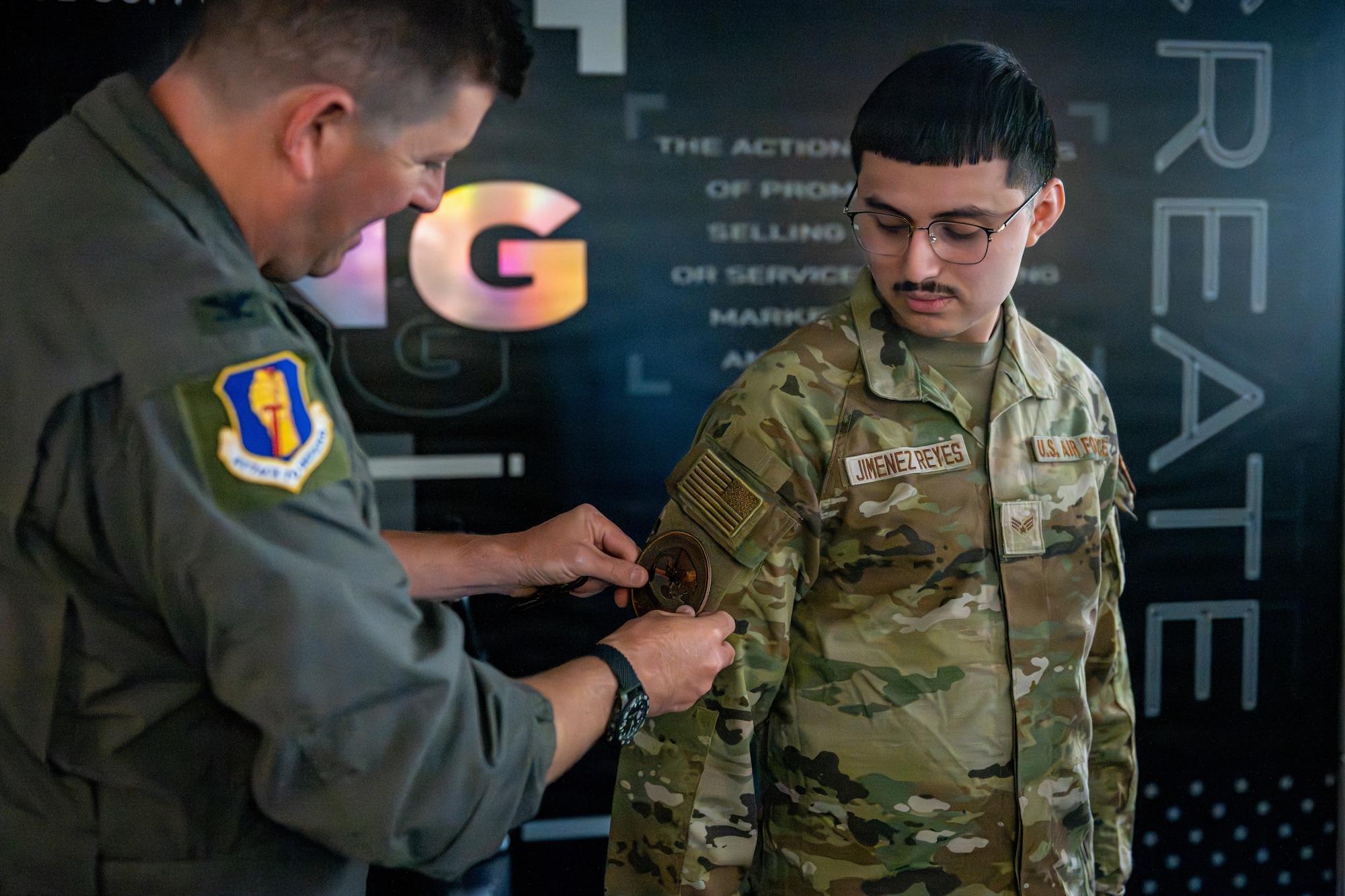 U.S. Air Force Col. Matthew Hoyt, 35th Fighter Wing deputy commander, left, presents Senior Airman Edwin Jiminez Reyes, 35th Force Support Squadron marketing and publicity communications specialist, with a patch during a Wild Weasel Walk-Through.
