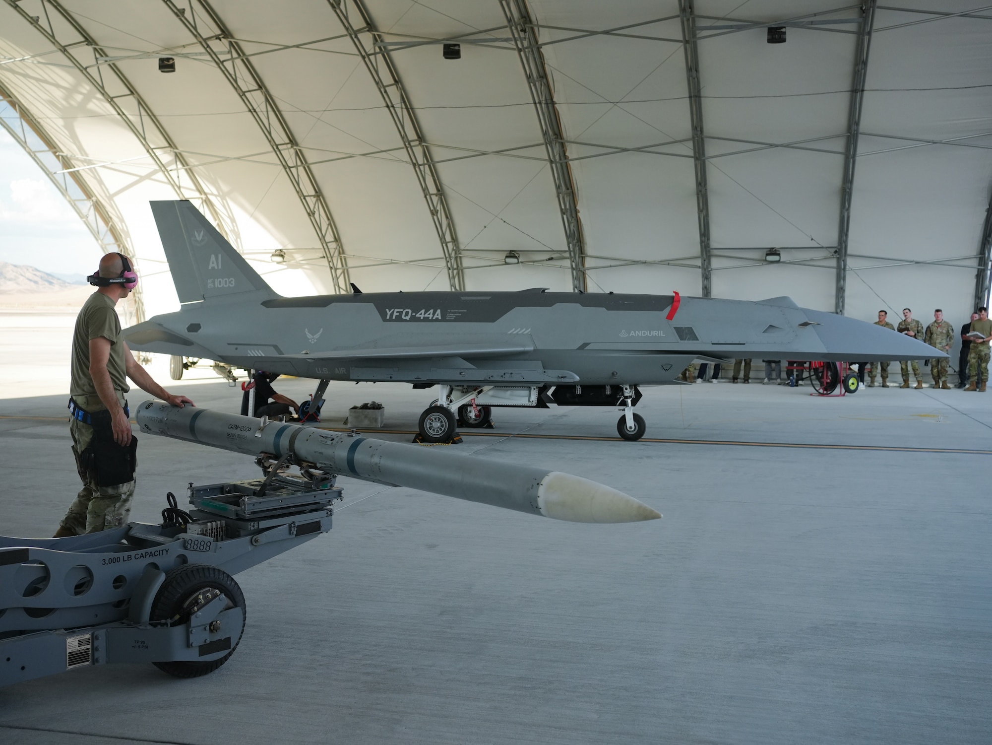 A U.S. Airman aligns a missile to load onto a YFQ-44A Fury aircraft.