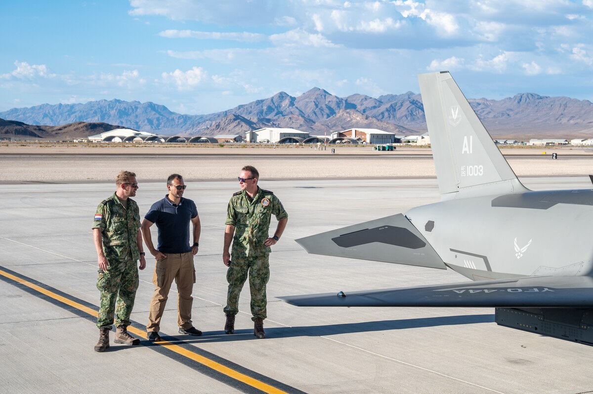 Three members of the Royal Netherlands Air and Space Force observe a U.S. Air Force YFQ-44A Fury aircraft on the flightline.