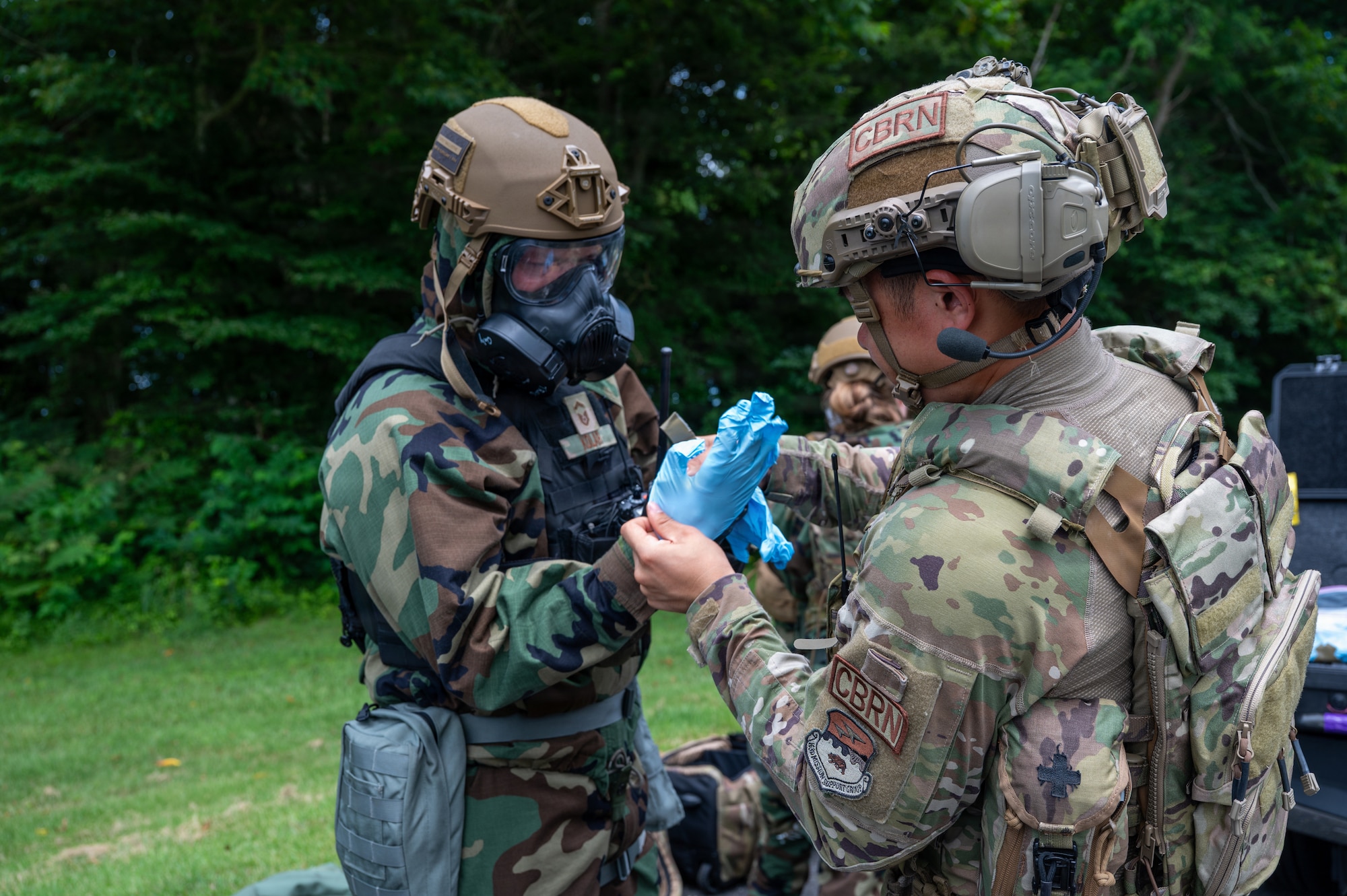 U.S. Air National Guard Airman 1st Class Kevin Yao, 163rd Civil Engineer Squadron emergency management specialist, California Air National Guard, right, assists U.S. Air National Guard Senior Master Sgt. Andrew Kolar, 179th Cyberspace Wing emergency management specialist, Ohio Air National Guard, with putting on protective gear before a chemical, biological, radiological and nuclear training scenario during Serow Samurai at Misawa Air Base, Japan, July 20, 2026.