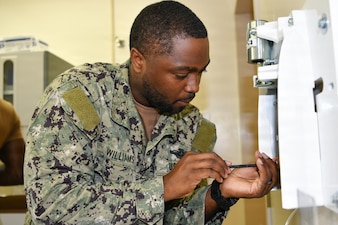 Navy Medicine Readiness and Training Command Pensacola Sailor, Hospital Corpsman 2nd Class, Biomedical Equipment Technician, Khalil Williams, assigned to Naval Hospital Pensacola, installs a dental X-ray unit motherboard mount, Naval Branch Health Clinic Naval Air Station Pensacola, Pensacola, Florida, June 24, 2026. From the fleet to hospitals and clinics Biomedical Equipment Technicians are specialized Hospital Corpsmen that install, maintain and repair medical equipment ensuring equipment is safe to use for patient care. (U.S. Navy photo by Mass Communication Specialist Seaman Jon Jezreel Andres)
