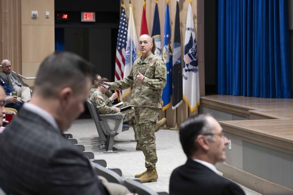 A service member in uniform presents from the stage of Bliss Auditorium to a crowd of military students.