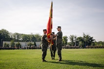 U.S. Marine Corps Col. Robert G. McCarthy III, the outgoing commanding officer of The Basic School, right, passes off the TBS colors to Col. Charles E. Miller II, the incoming commanding officer of TBS, during a change of command ceremony at Marine Corps Base Quantico, Virginia, July 15, 2026. During the ceremony, McCarthy relinquished command of TBS to Miller. (U.S. Marine Corps photo by Cpl. Joshua Barker)