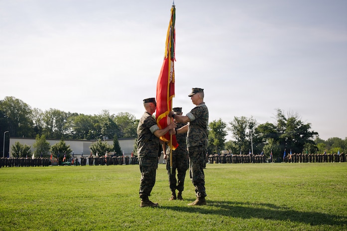 U.S. Marine Corps Col. Robert G. McCarthy III, the outgoing commanding officer of The Basic School, right, passes off the TBS colors to Col. Charles E. Miller II, the incoming commanding officer of TBS, during a change of command ceremony at Marine Corps Base Quantico, Virginia, July 15, 2026. During the ceremony, McCarthy relinquished command of TBS to Miller. (U.S. Marine Corps photo by Cpl. Joshua Barker)