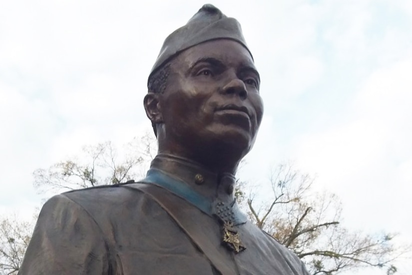 A bronze statue of a man in a World War I-era uniform and wearing a Medal of Honor stands outside.