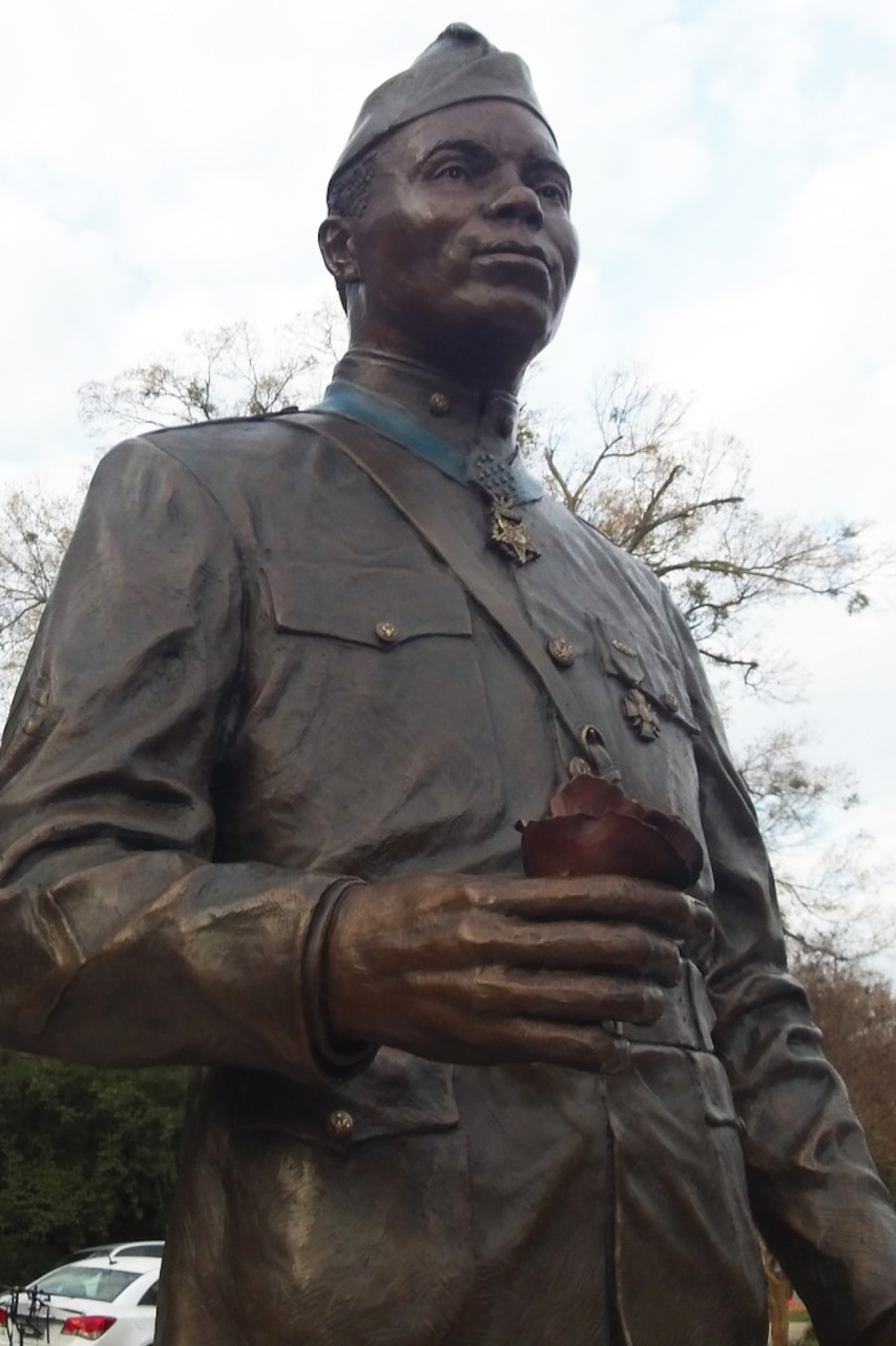 A bronze statue of a man in a World War I-era uniform and wearing a Medal of Honor stands outside.