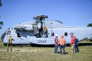 Aircraft recovery personnel from the U.S. Air Force, U.S. Marine Corps and U.S. Navy, alongside industry and allied partners, prepare a CH-53 helicopter to hoist an F-15 Eagle training aircraft during the F-35 Joint Program Office Advanced Crash Damaged or Disabled Aircraft Recovery (CDDAR) course at Volk Field Combat Readiness Training Center, Wisconsin, July 13, 2026. The advanced CDDAR course challenged participants to solve complex recovery scenarios while improving joint integration, critical thinking and multinational interoperability. (U.S. Air National Guard photo by Master Sgt. Regina Young)