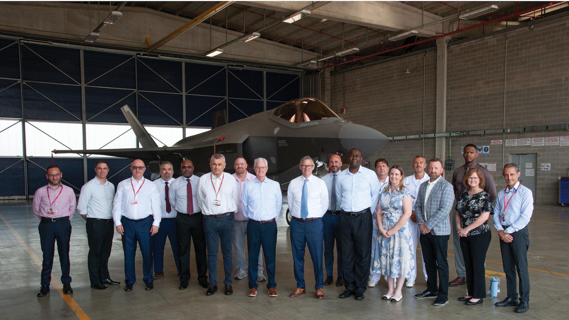 A group photo of international partners with an F-35 in the background.